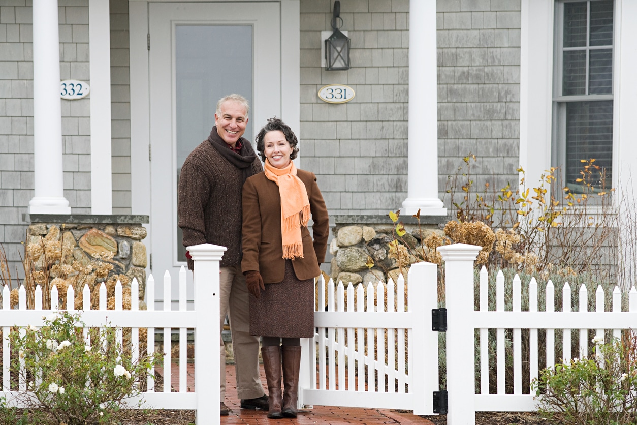 A retired couple stands outside their new home they bought in the winter.