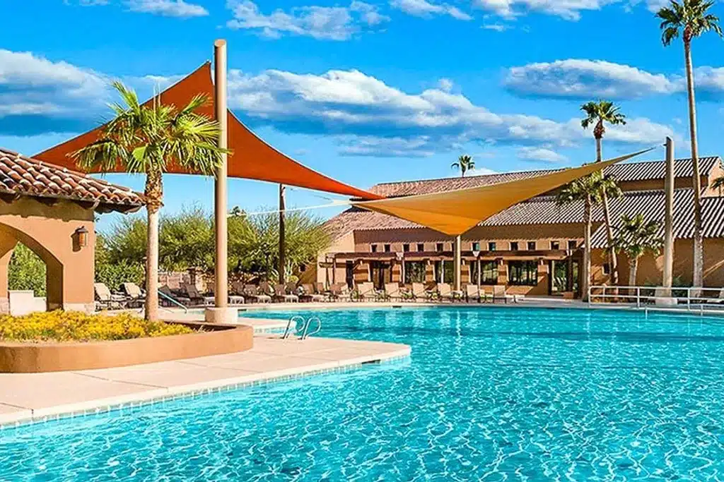VIew of the outdoor pool and patio on a sunny day at Robson Ranch. 
