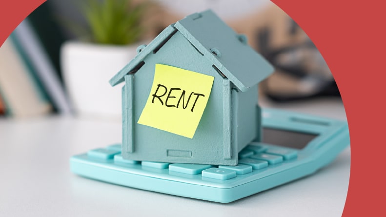 A model house placed on a calculator and a sticker with the word "Rent."