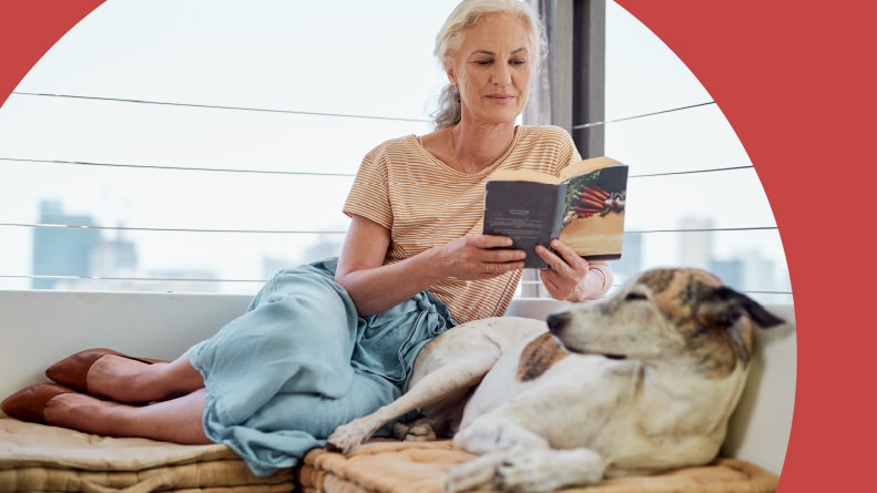 A woman reading with her dog on the balcony of her 55+ apartment.