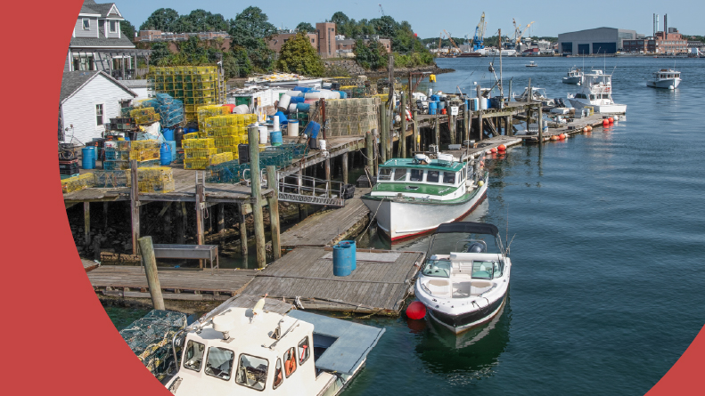 Fishing boats dock beside stacks of lobster traps at a wharf in Portsmouth, New Hampshire.