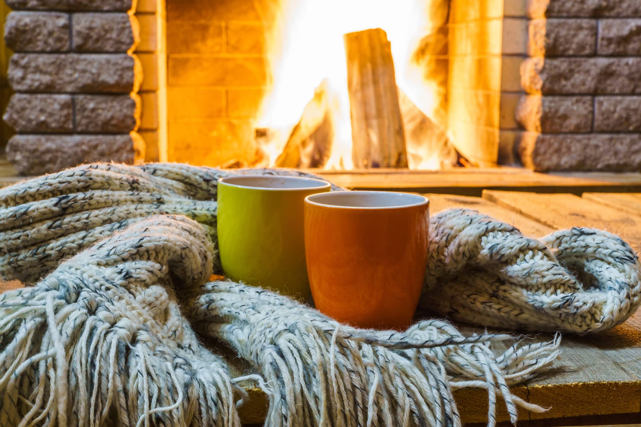 Two mugs for tea or coffee near a cozy fireplace in a country house.