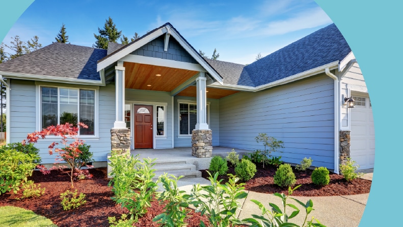A light blue house with a stone porch and concrete walkway in the Northwest region of the U.S.