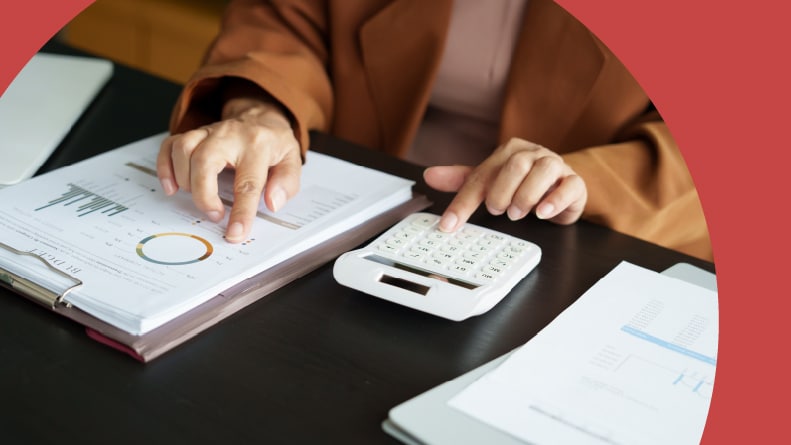 A 55+ woman using a calculator while looking over her finances.