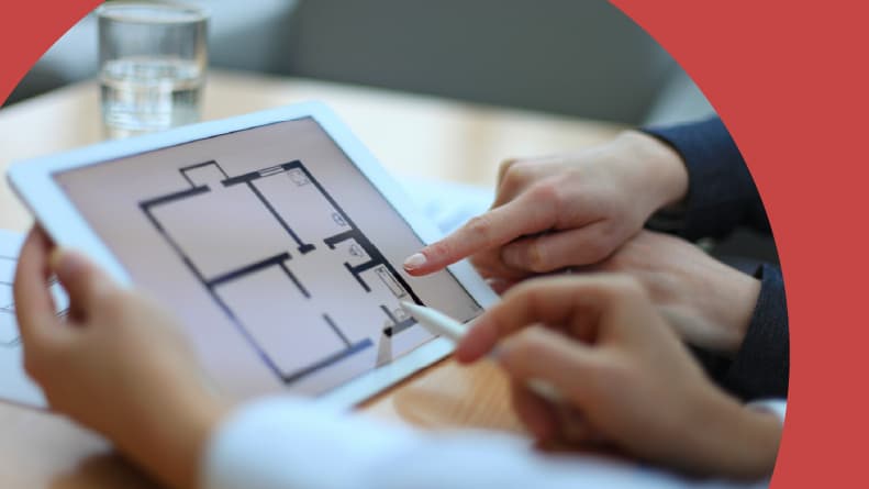 A real estate agent showing floor plans to a 55+ homebuyer.