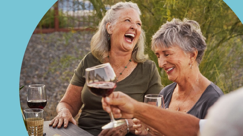 Friends laughing while having an outdoor dinner in their 55+ community.