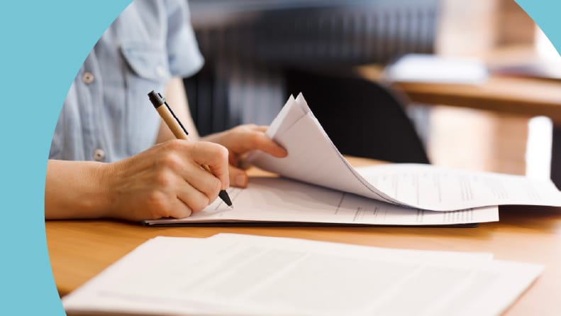 A 55+ woman's hands with a pen signing rental documents.
