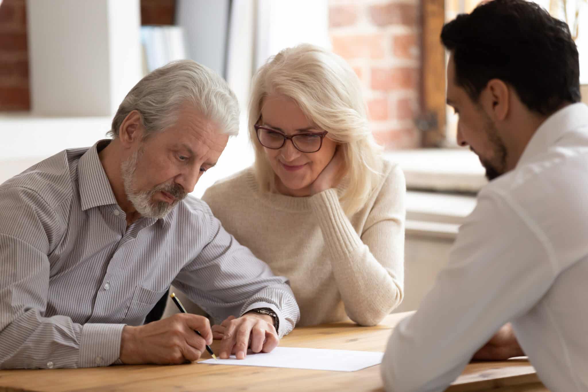 Senior couple signing paperwork with a real estate agent.