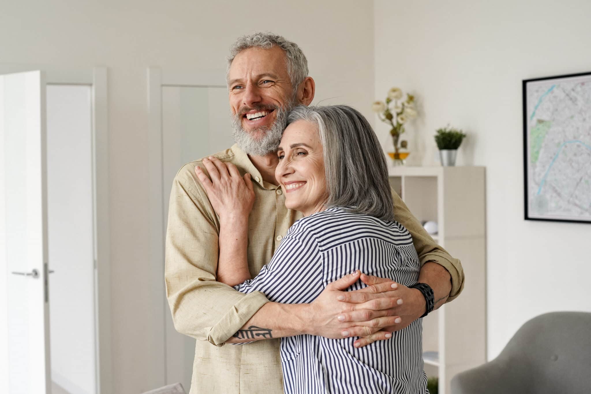 Senior couple embracing and smiling after buying a new home.