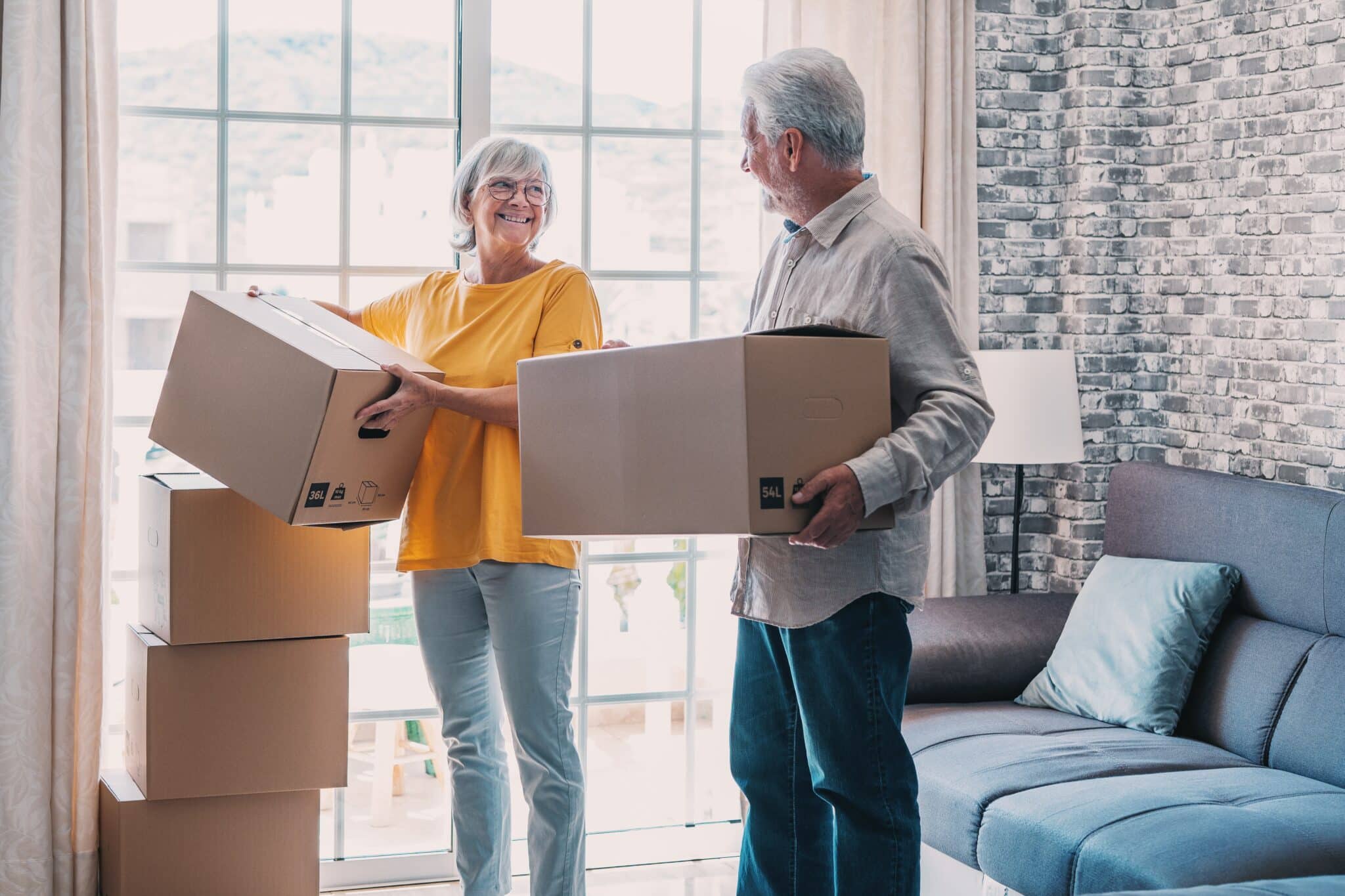 Senior holding moving boxes in their new home.