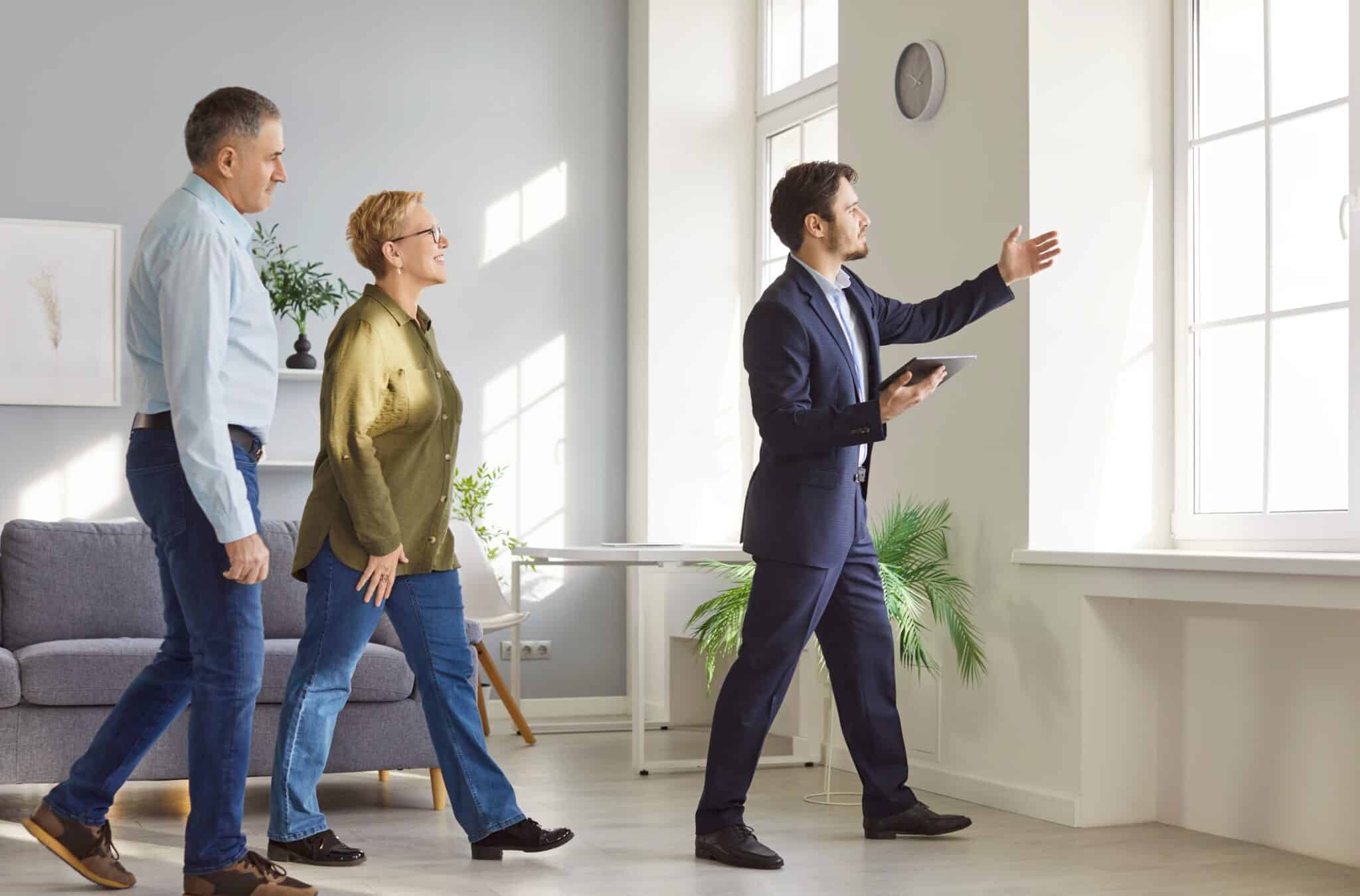 Senior couple viewing a property with a real estate agent.