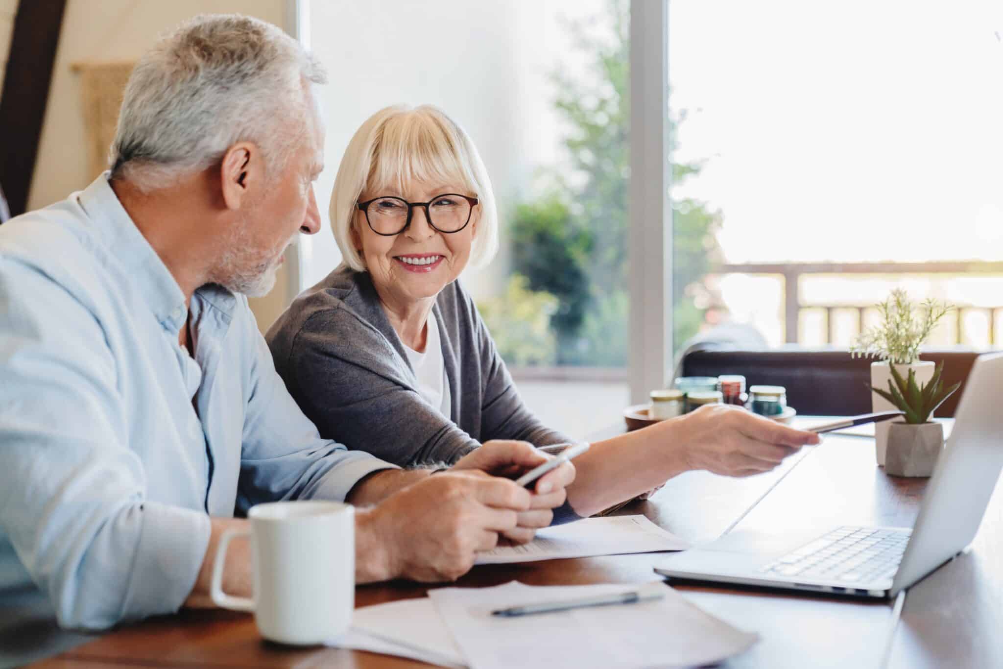 Senior couple sitting at a table doing paperwork together.