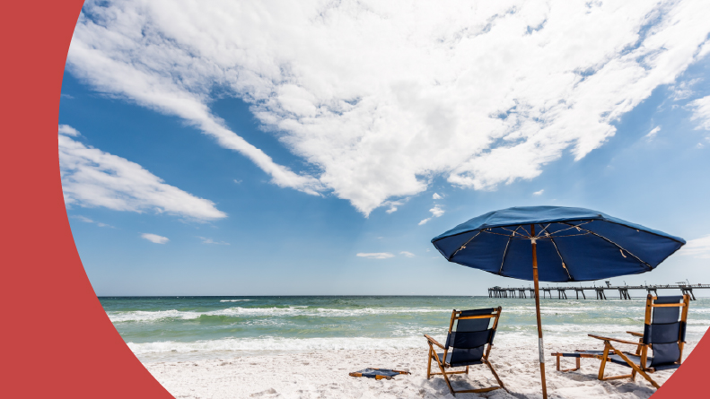 Two empty beach chairs and an umbrella near Okaloosa Fishing Pier in Fort Walton Beach, Florida during the day.