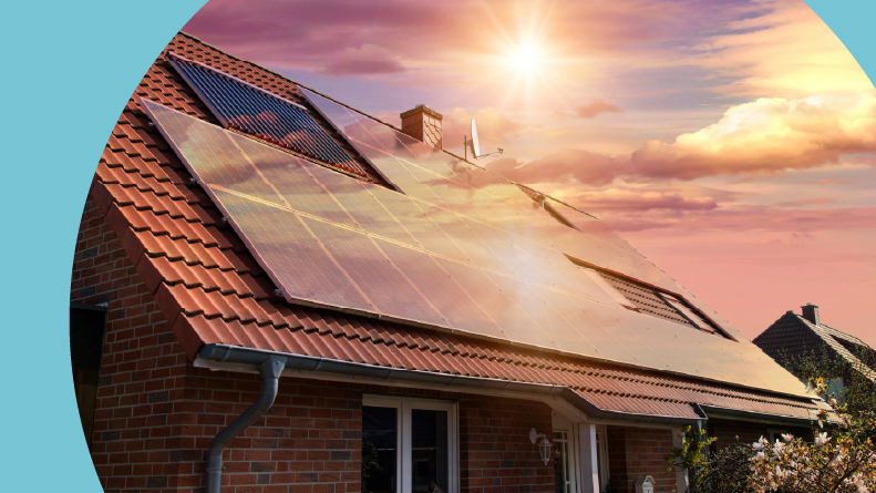 Photovoltaics on the red roof of a house at sunset.