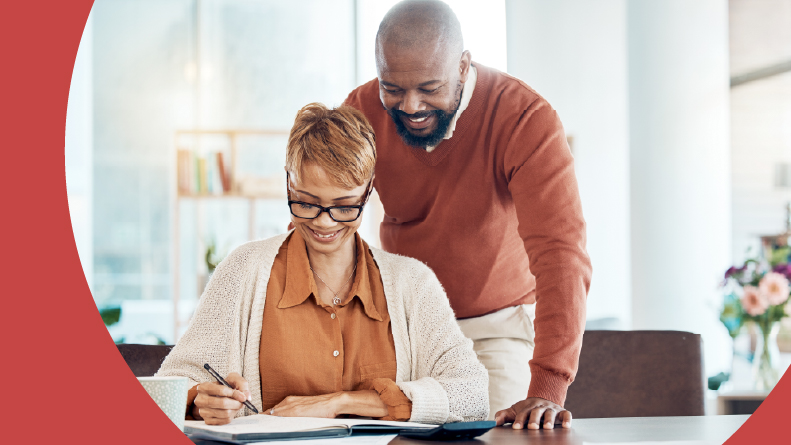 A 55+ man and woman happy at home while looking over their electric bill.