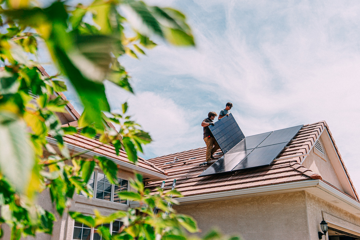 Workers install solar panels on the roof of a home in a 55+ community.