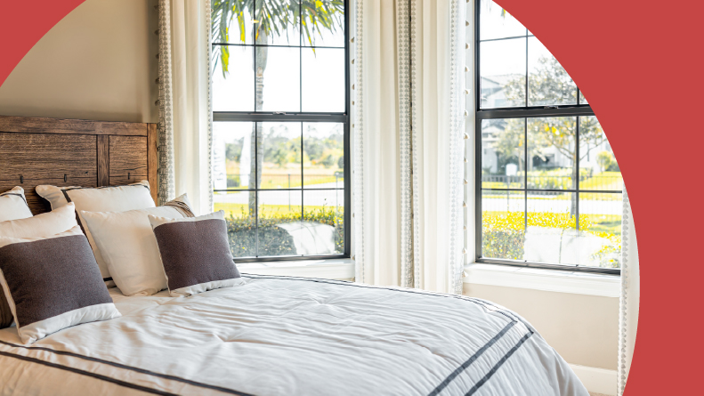 A bed with decorative pillows in a bedroom with a bay window in Florida.