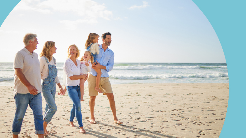 Grandparents, parents and children walking on a beach.