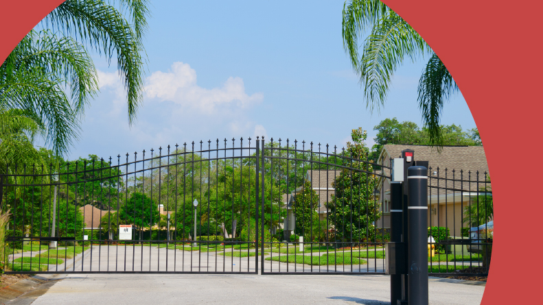 Entrance gate to a gated community with lush green trees and grass.