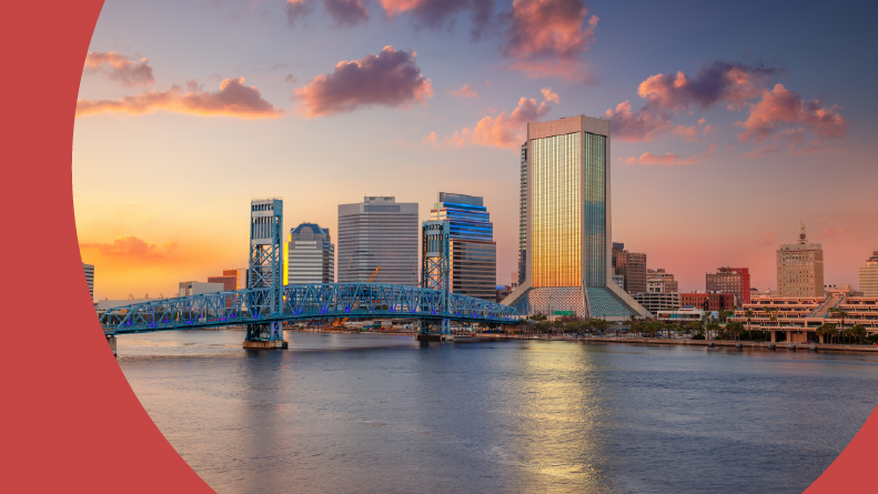 The cityscape of Jacksonville, Florida with a reflection of the city skyline in the water at sunset.