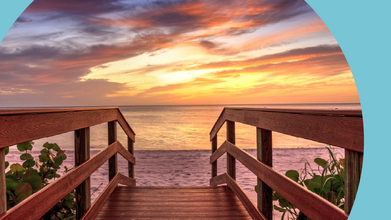 A boardwalk leading to a sunset over North Gulf Shore Beach along the coastline of Naples, Florida.