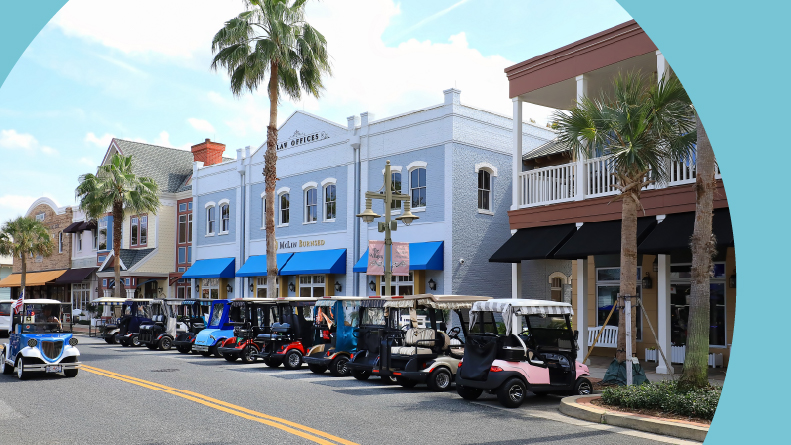 Colorful golf carts parked on a main street at downtown Sumpter Landing in The Villages, Florida.