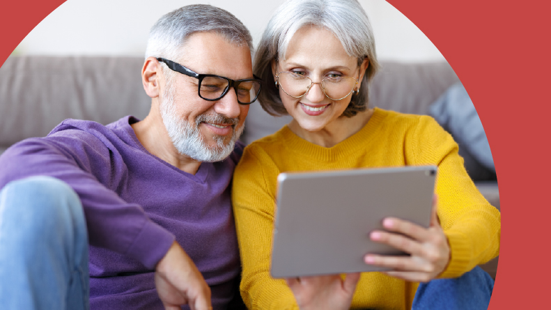 A 55+ couple looking at Del Webb Explore communities on a tablet at home.