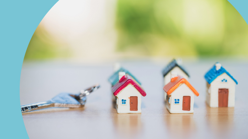 Mini houses beside a key on a table.