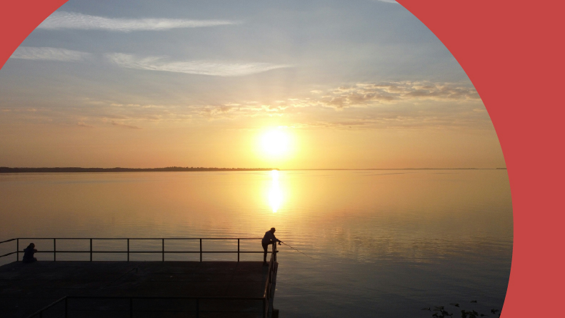A sunrise over people fishing on a dock in Leesburg, Florida.