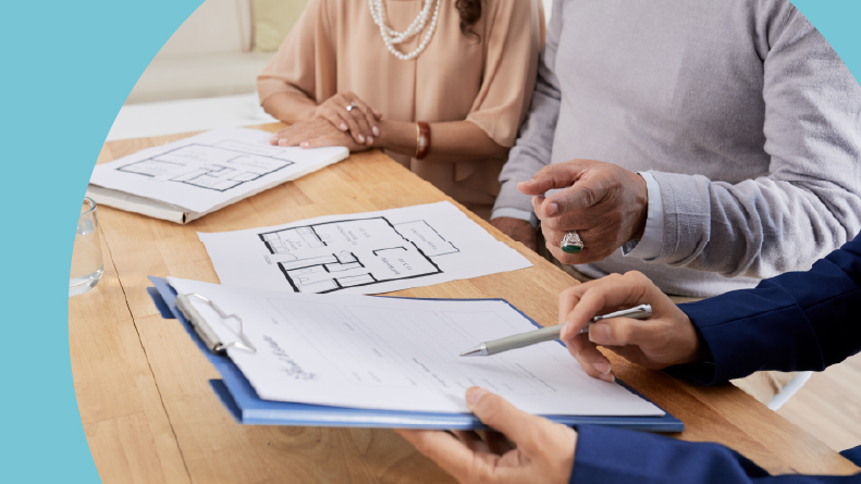 A real estate agent sitting at a wooden table and helping her senior clients choose an apartment.