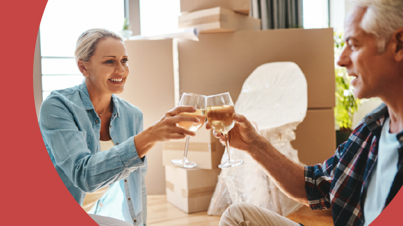 An active adult couple toasts with wine as they move into their new apartment.