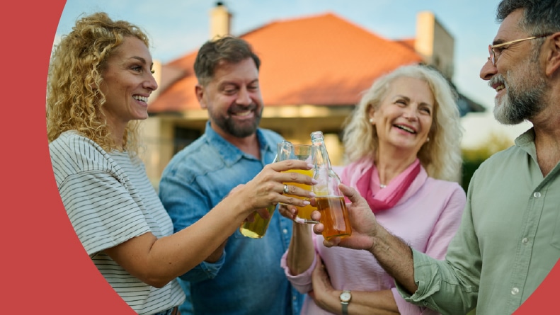 A group of 55+ friends laughing and having fun while raising their beer bottles for a toast.