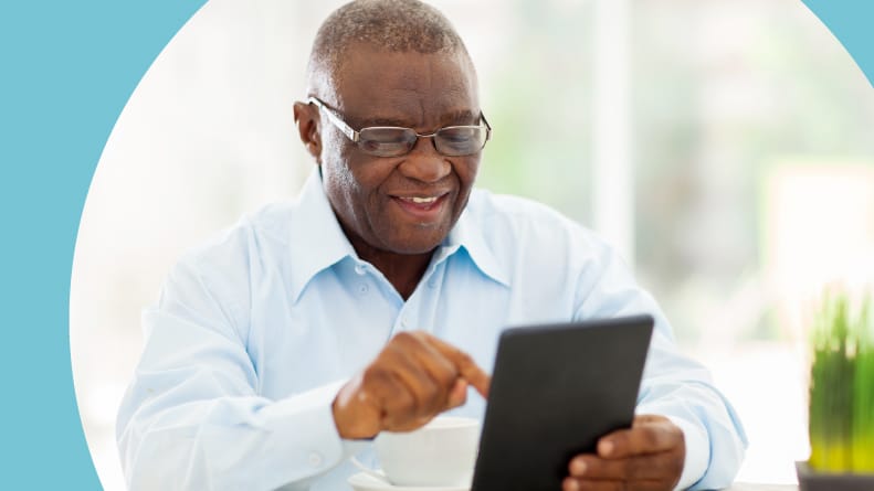 A cheerful senior man enjoying an online hobby on a tablet at home.