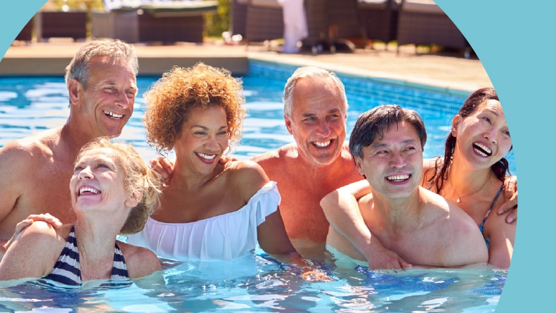 A group of 55+ friends relaxing In an outdoor pool during summer.