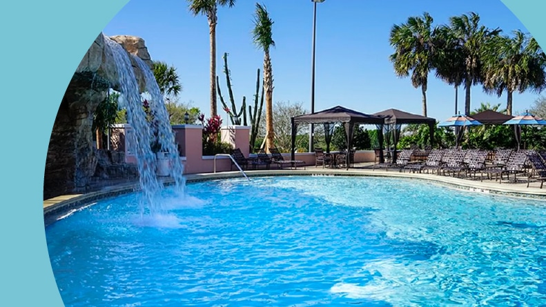 Palm trees and lounge chairs surrounding an outdoor, resort-style pool at The Villages in Florida.