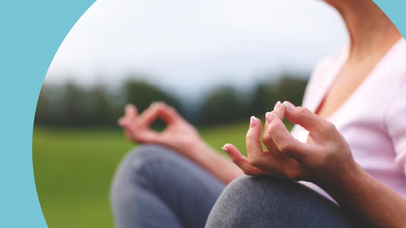 Closeup on the hands of a senior woman as she meditates while practicing yoga.