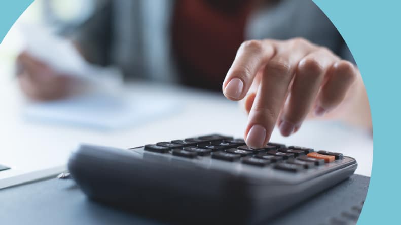 Close up on a woman's hand using a calculator to do taxes.