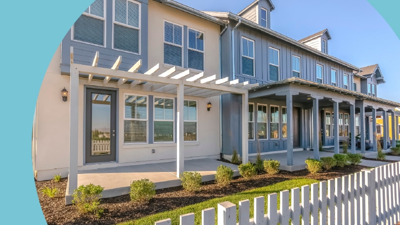Townhouses with yards and a white fence.
