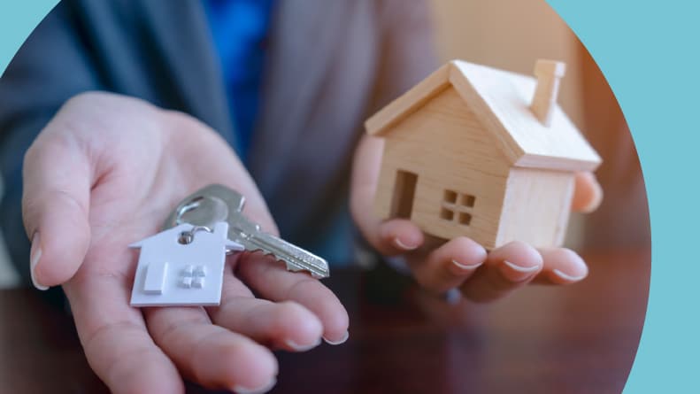 A real estate agent holding a house model and keys.