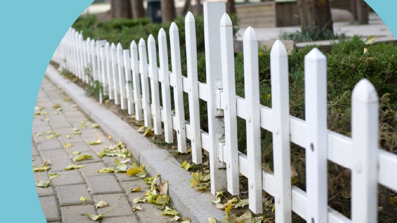 A white fence along a brick pathway.