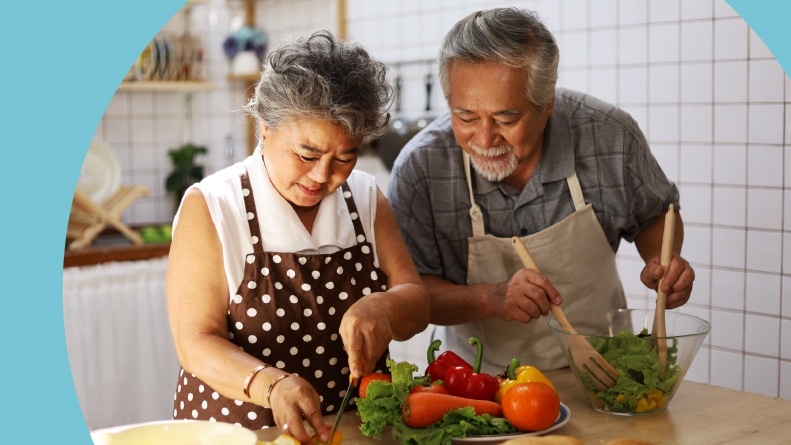 A 55+ couple cooking a healthy meal at home.