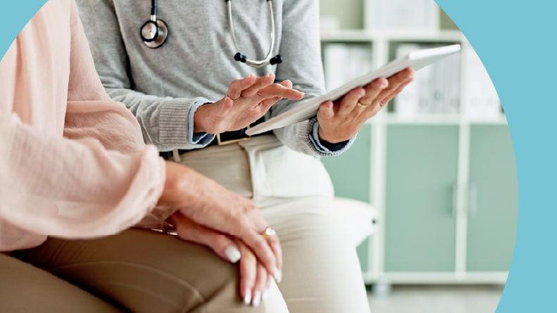 The hands of a doctor with a tablet and a 55+ patient.