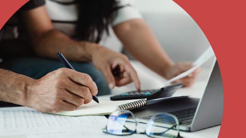 A 55+ couple doing their taxes with a calculator and filling form.