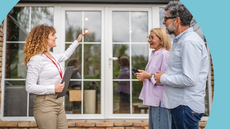 A real estate agent happily showing a home to a 55+ couple.