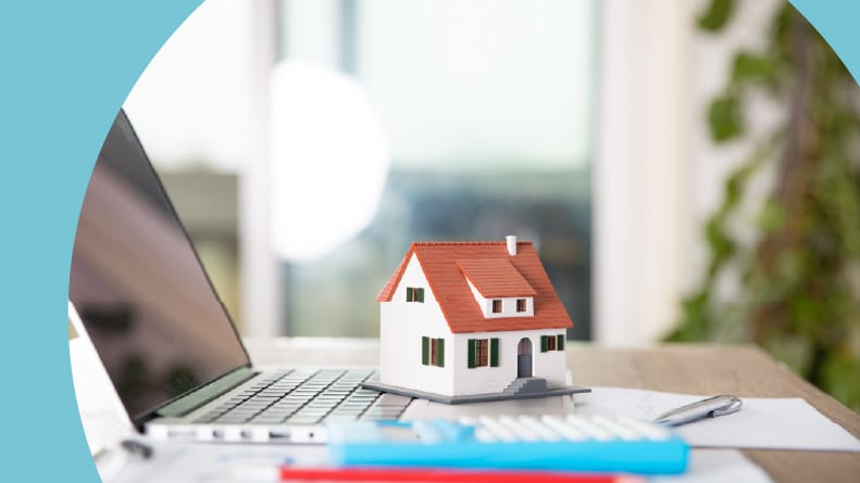 A small model house sitting on a laptop. Real estate market forecast analysis.