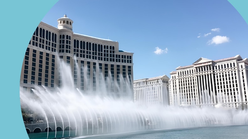 The Bellagio Hotel and Casino with its iconic fountain show in Las Vegas, Nevada, under a clear blue sky.