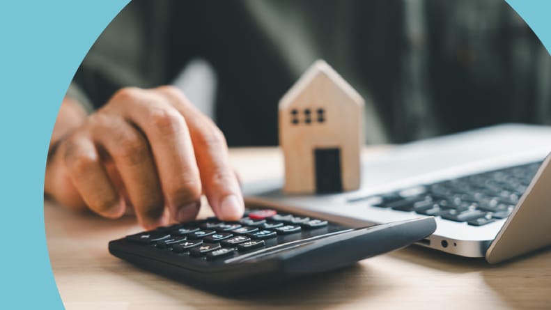 A 55+ homeowner using a calculator and a laptop to calculate property taxes.