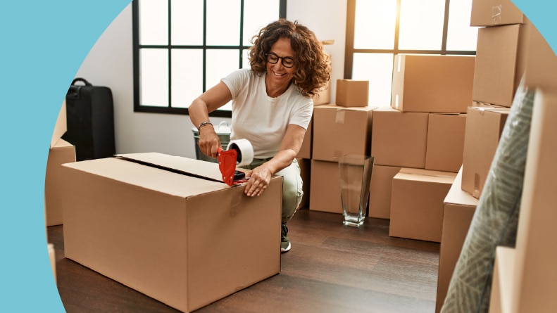 A 55+ woman packing cardboard boxes while downsizing.