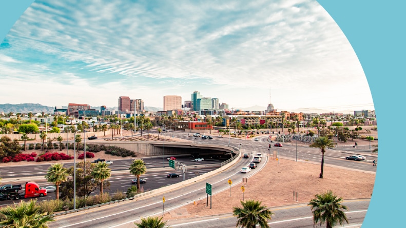 A highway in Arizona with the Phoenix skyline in the background.