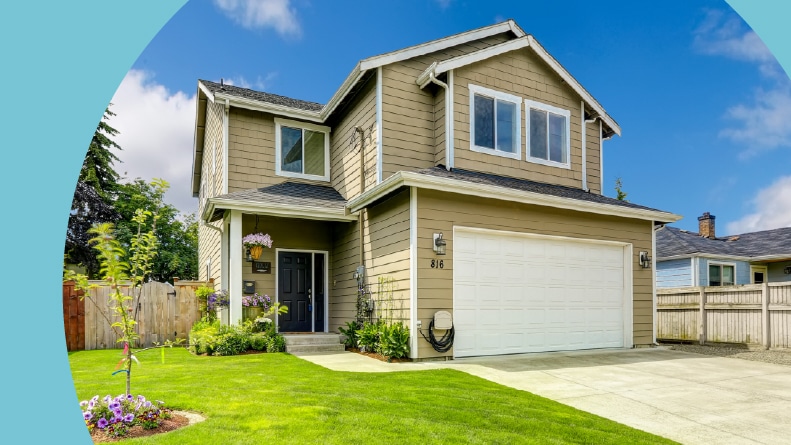 A two-story house exterior with a white garage door, green lawn, and driveway.